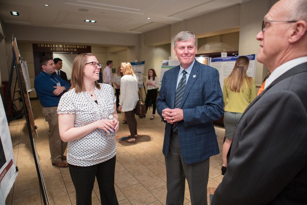 President T. Haas and Doctor Potteiger speaking with a student presenter